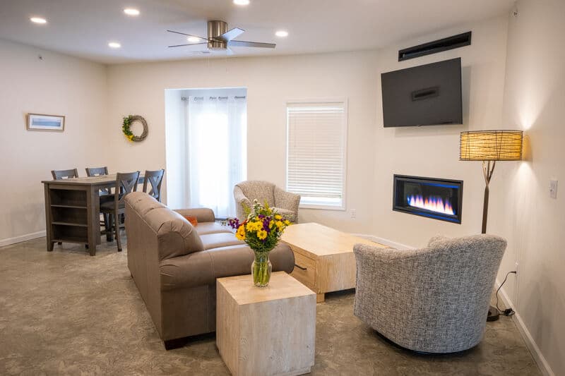 open living room are with fireplace and flat screen tv on wall with dining table against far walll.