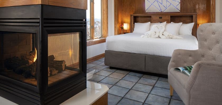 Hermann Hill suite with a king bed, swan towels, comfortable seating, and a lit fireplace.