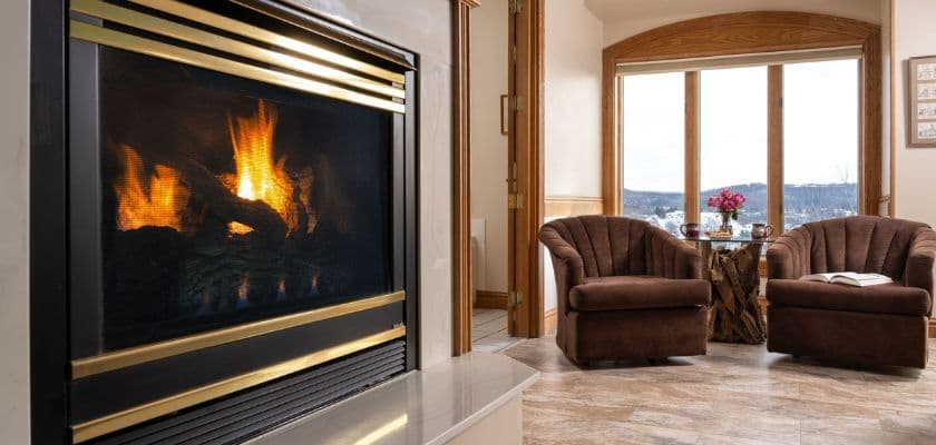 A cozy living room featuring a modern fireplace, two brown chairs, and large windows with a view.