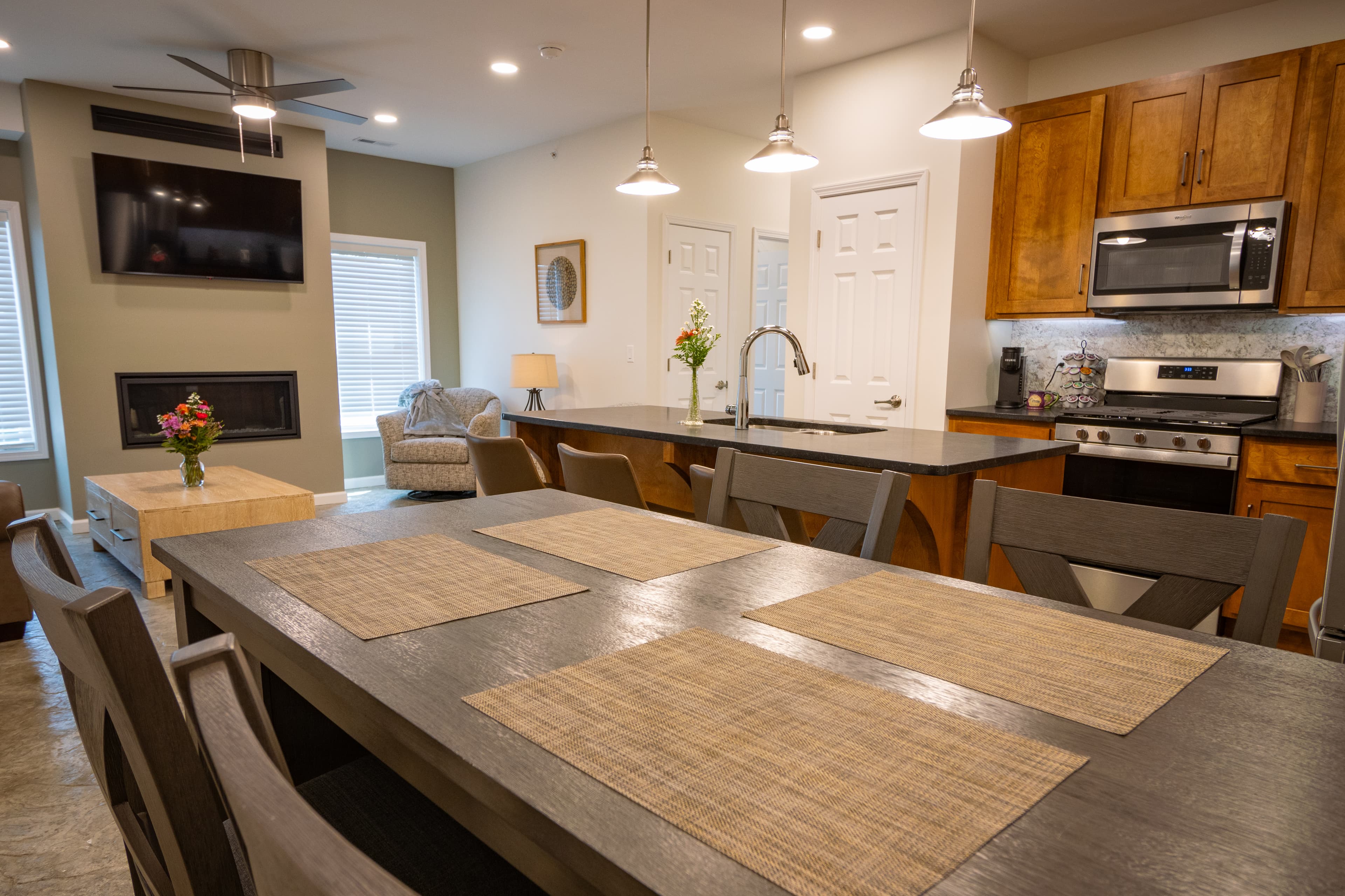 A modern kitchen and dining area featuring a large table, wooden cabinetry, and a cozy seating area with a sofa.