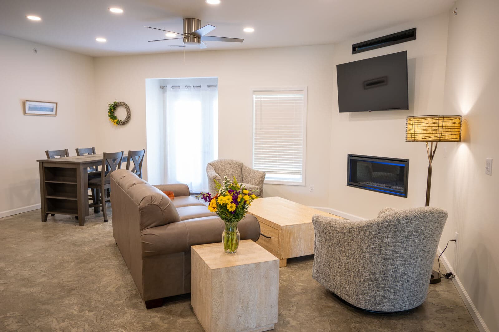 Cozy modern living room with a seating area, dining table, and decorative flowers.