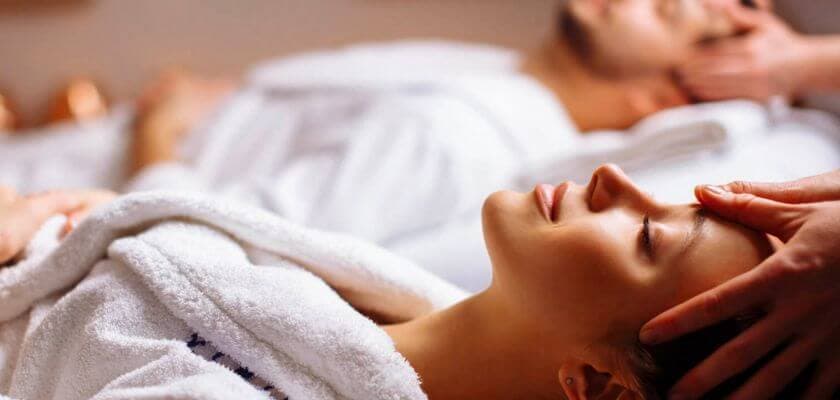 A woman relaxes during a spa treatment as a person gives her a forehead massage.