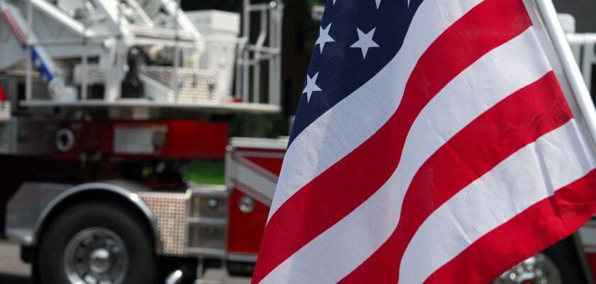 An American flag is prominently displayed in front of a fire truck.