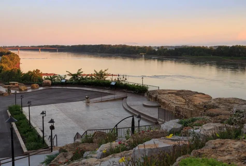 View from the top of a hill full of stones includes an event space and large rocks that look over the river in the background