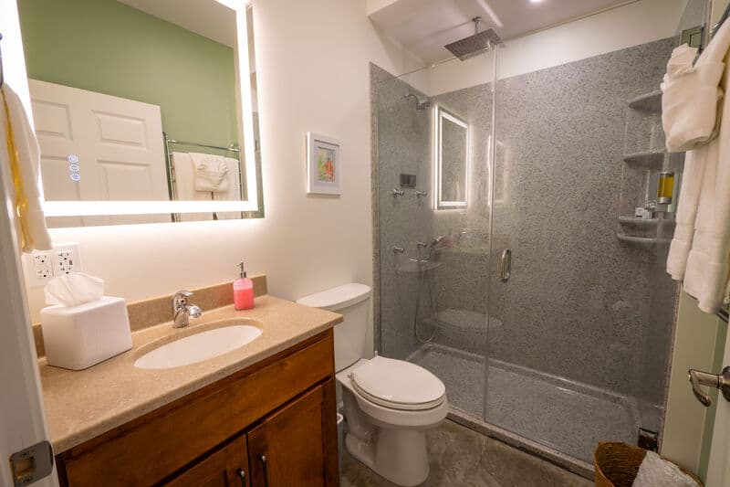 A modern bathroom featuring a glass shower, a wooden vanity, and decorative accents.