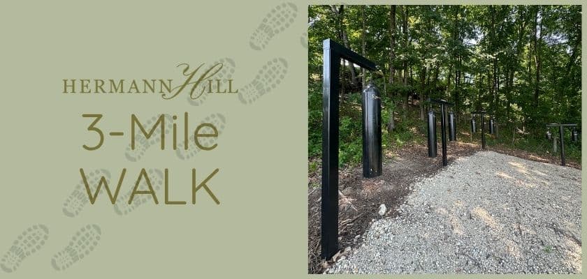 Image of a nature trail at Hermann Hill with a "3-Mile Walk" sign and fitness stations along a gravel path.