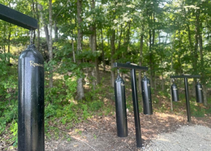 Gongs labeled Passion and Strength hang from wooden posts along Hermann Hill's Forest of Gongs trail. Gongs labeled Passion and Strength hang from wooden posts along Hermann Hill's Forest of Gongs trail.