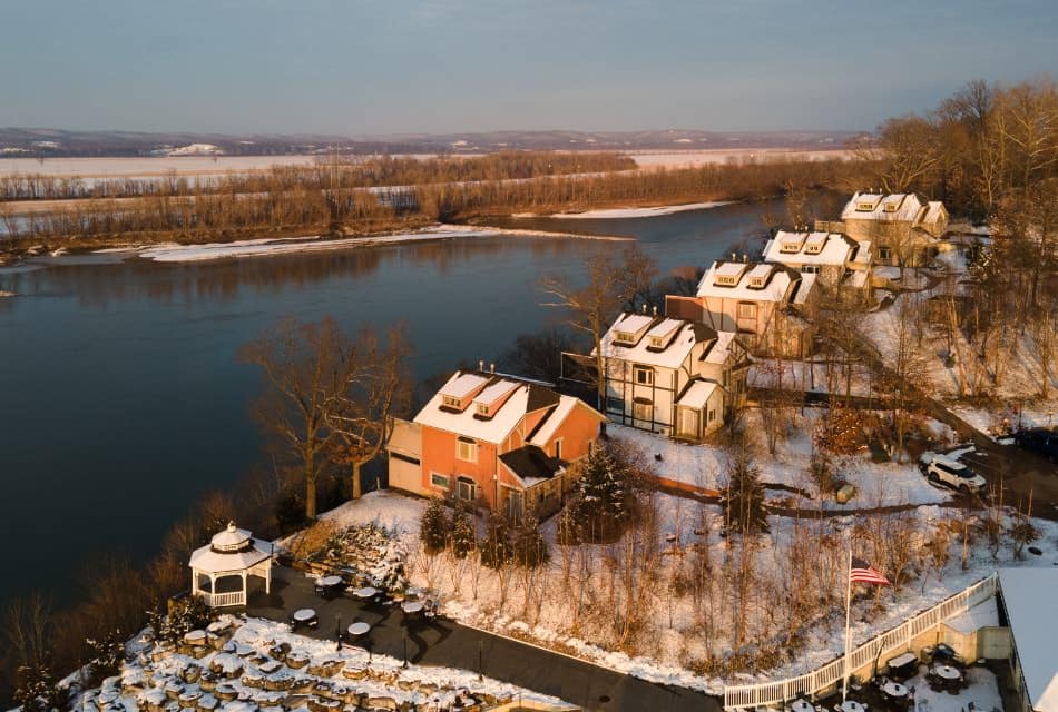 Exterior aerial view of the property covered by snow and near a river