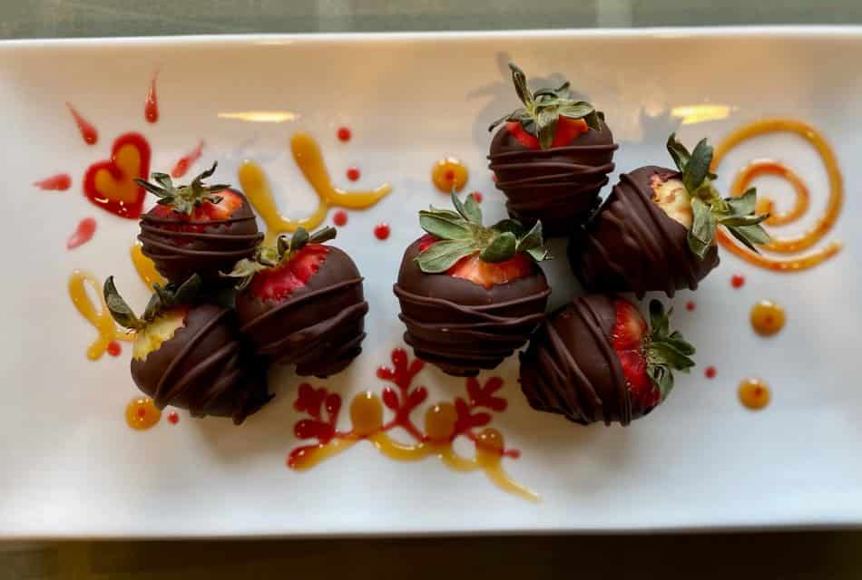 Close up view of rectangular white dish with chocolate covered strawberries