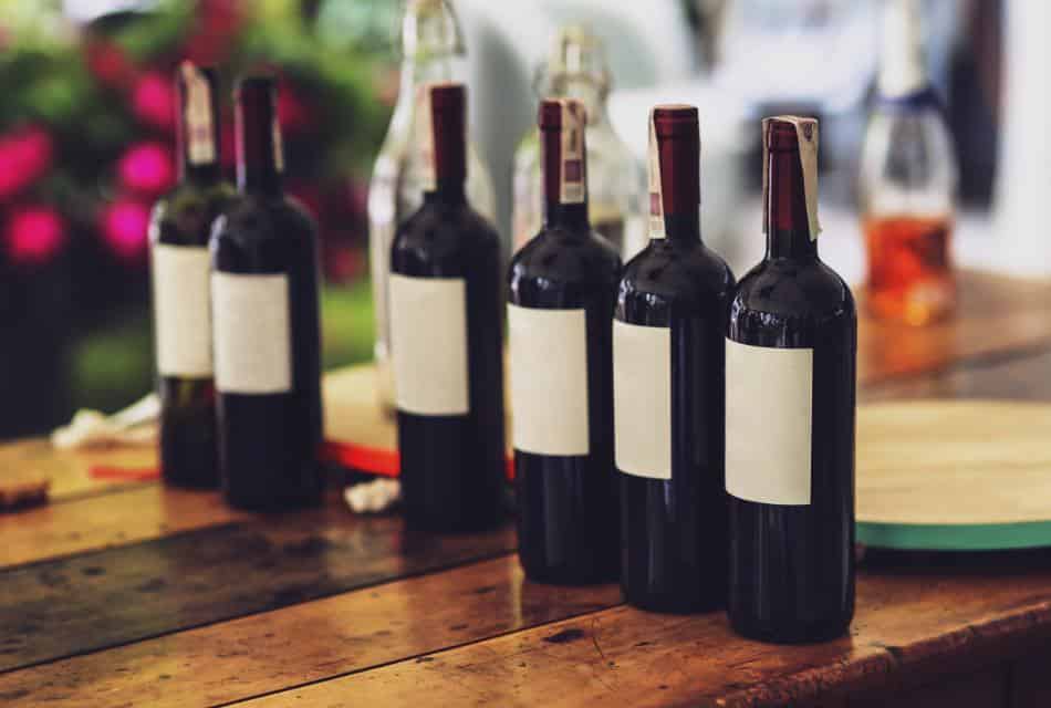 Multiple bottles of red wine with blank labels on a wooden table