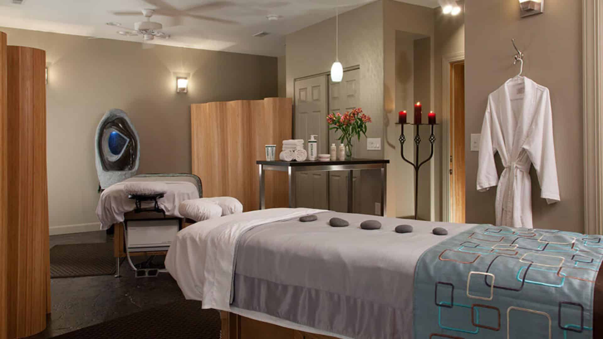 Serene spa room with massage table, hot stones, terry robe, and dim lighting